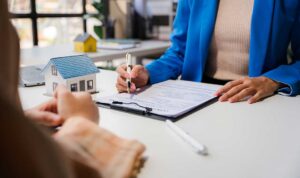 Homeowner reviewing an insurance policy beside repair receipts, photos, and a damaged household appliance.